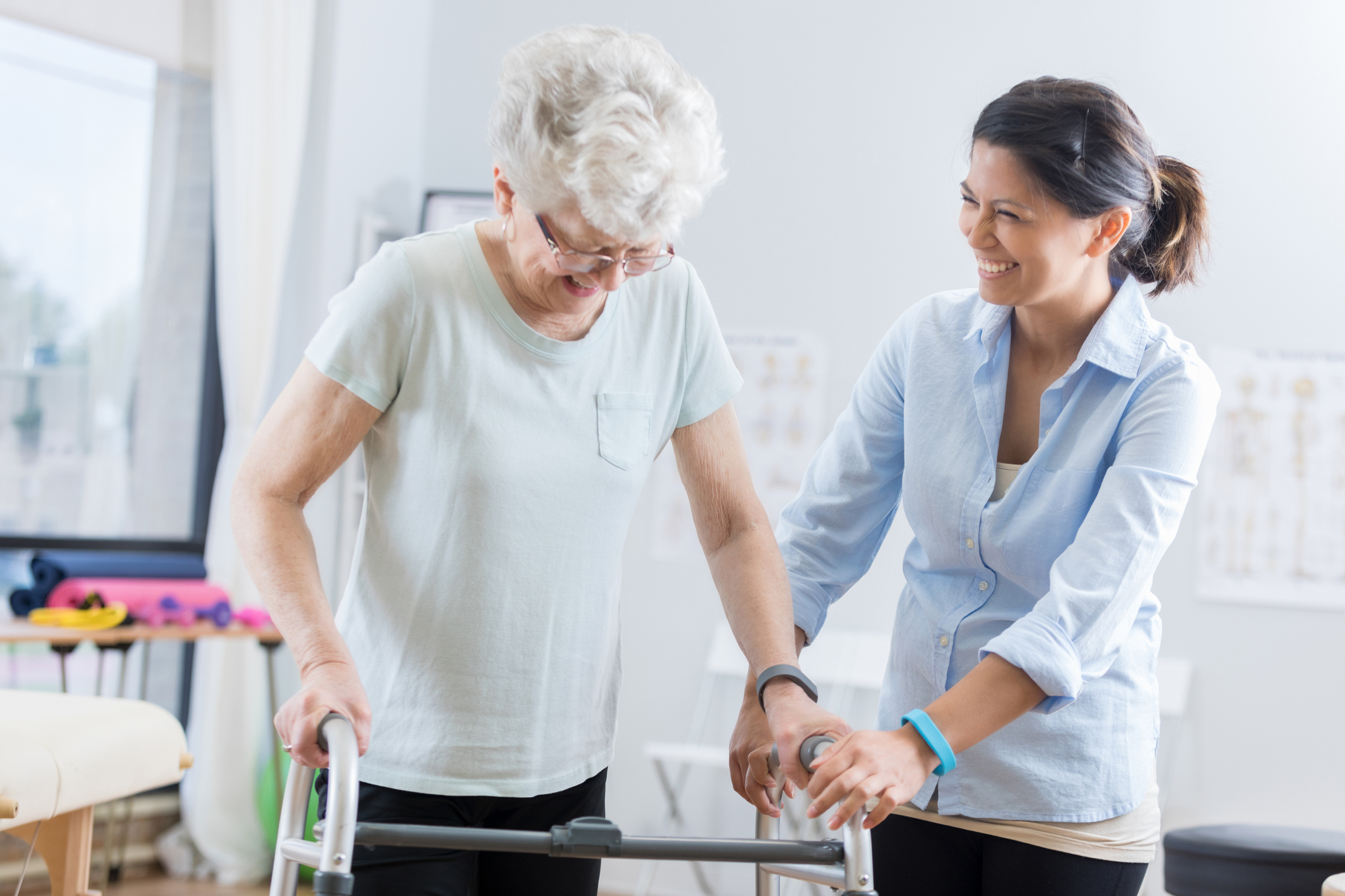 Healthcare professional helps senior woman walk with a walker